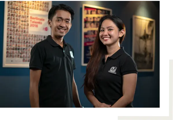 man and woman posing in an office with movie posters